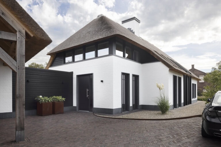 Entreegevel villa Budel met rieten kap, wit metselwerk en donkere kozijnen
