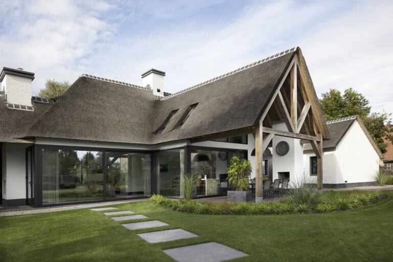 Tuingevel villa Budel met houten kapconstructie, glaspartijen en rieten kap
